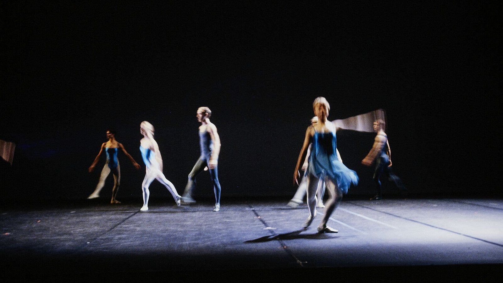 The full company spread across a darkened stage